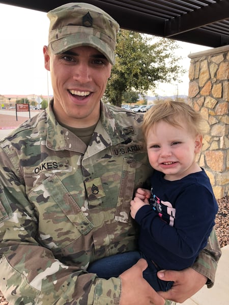 Image of veterans coding scholarship recipient Michael holding his 2-year-old daughter.